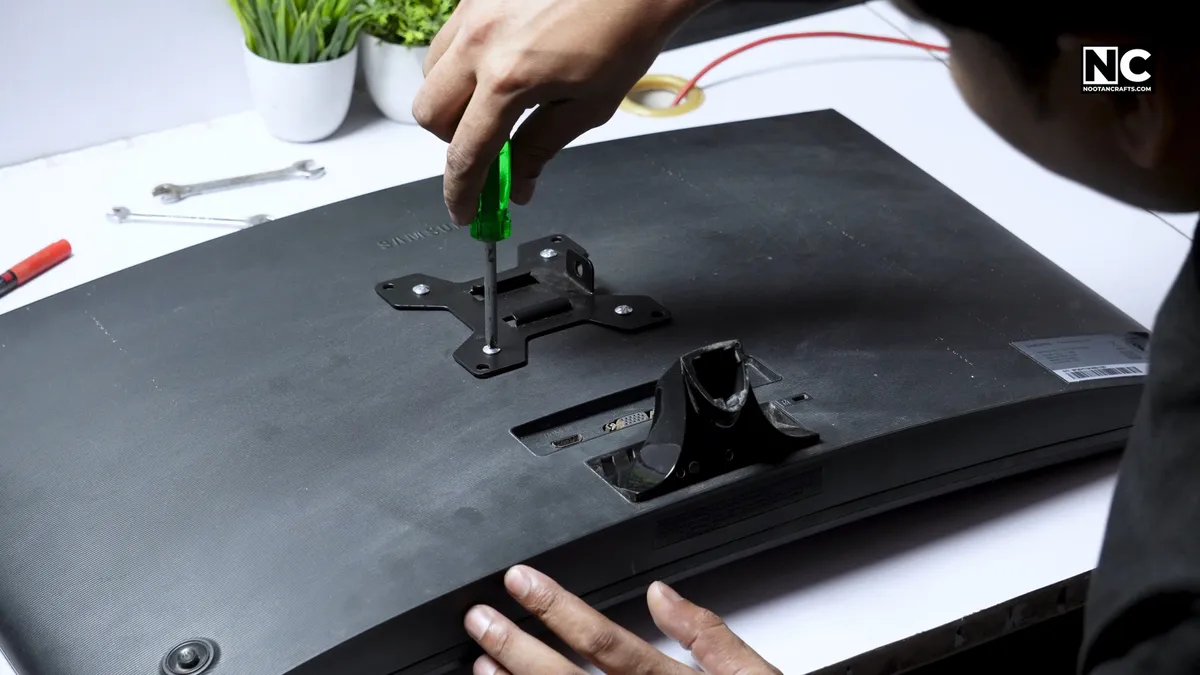 VESA base plate aligned with the four mounting holes on the back of a monitor